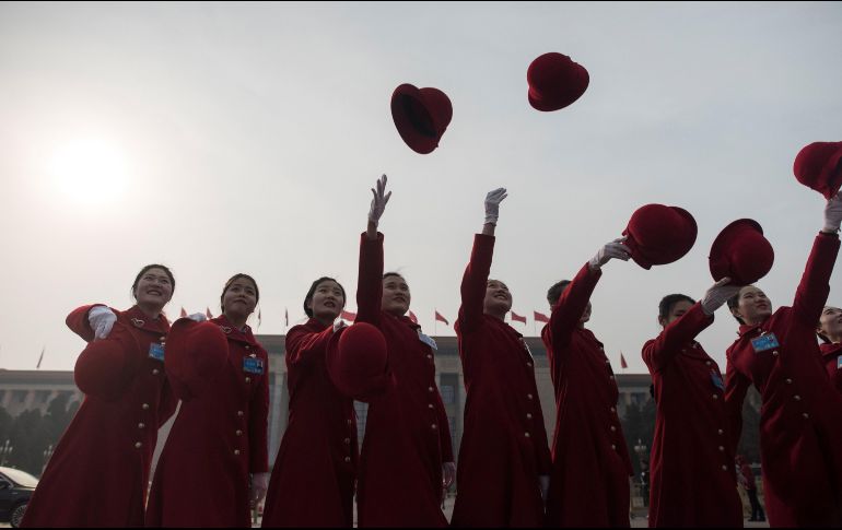 Edecanes arrojan sus sombreros para una foto, durante la primera sesión del Congreso Nacional del Pueblo en Pekín. AFP/F. Dufour