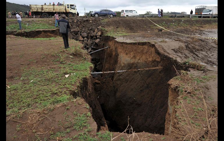 Vehículos pasan junto a un socavón en una vía dañada por fuertes lluvias en Maai-Mahiu, Kenia. Las  precipitaciones han provocado cortes en las carreteras hacia la frontera con Tanzania. AFP/T. Karumba