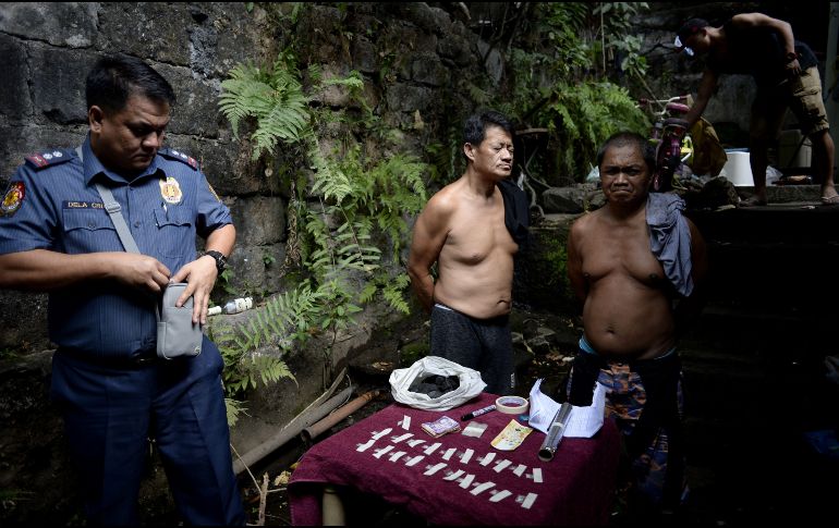 Dos presuntos traficantes de drogas aguardan junto a productos confiscados en un operativo policial en Manila, Filipinas. El presidente Rodrigo Duterte anunció ayer que retirará al país de la Corte Penal Internacional por tratar de investigar su campaña contra las drogas. AFP/N. Celis