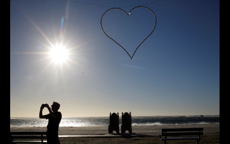 Un grupo de turistas pasean y toman fotos en la playa de Camps Bay en Ciudad del Cab, Sudáfrica. EFE / K. Ludbrook