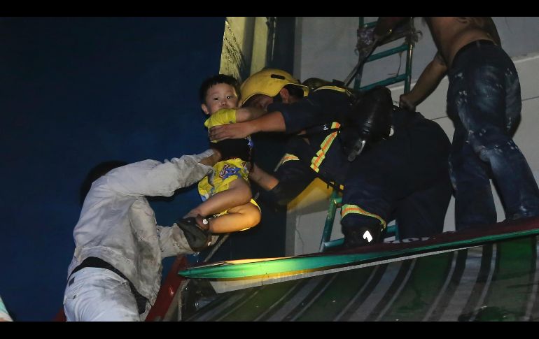Un niño es rescatado de un complejo de condominios incendiado en Ciudad Ho Chi Minh, Vietnam. El fuego ha provocado la muerte de al menos 13 personas. AP/VnExpress