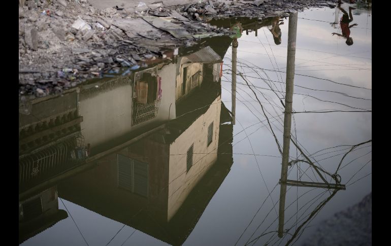 Personas se reflejan en un charco en Manila, Filipinas. AFP/N. Celis