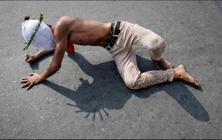 Penitentes se arrastran por el suelo en procesión hacia una iglesia, en San Pedro Cutud. EFE/R. Cristino