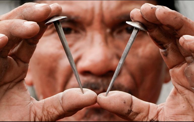 El penitente Rubén Enaje muestra dos clavos que serán utilizados para crucificarle por trigésimo segundo año. EFE/R. Cristino