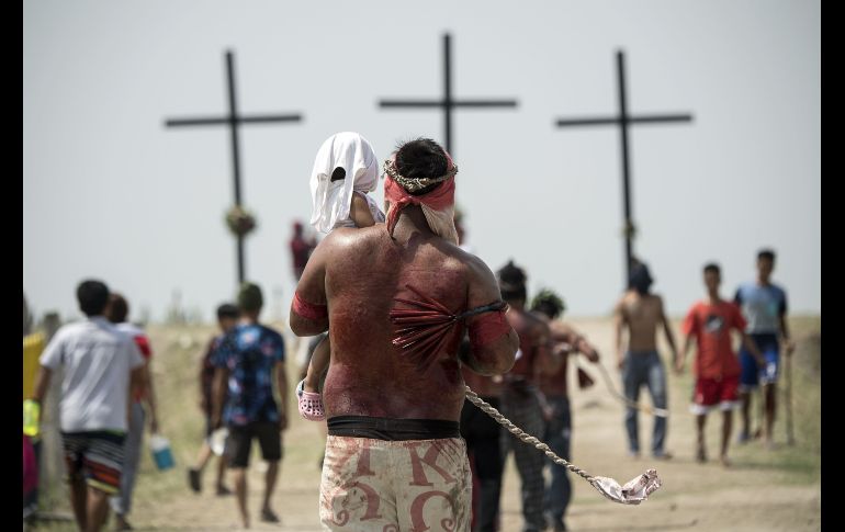 Un hombre que se autoflageló se dirige junto a su hija hacia la ceremonia de crucifixión en San Fernando. AFP/N. Celis