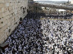 Bajo un calor bochornoso y protegiéndose del sol con sus mantos de rezo, los hombres judíos rezan en el área del Muro reservada para ellos, y las mujeres en uno de los laterales. AFP/M. Kahana