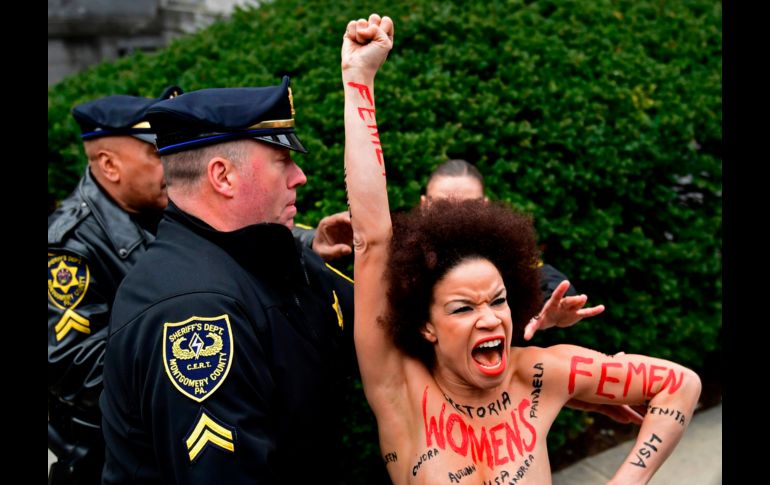 Una mujer en toples, que lleva escrito en su cuerpo: 