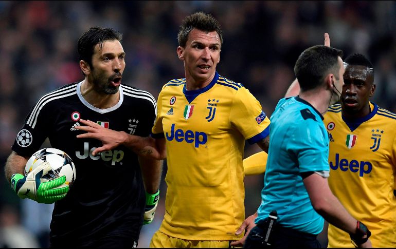 Buffon (I) no pudo intentar atajar la pena máxima que significó la eliminación de la Juventus ya que fue expulsado por el colegiado Michael Oliver (D). AFP/O. del Pozo