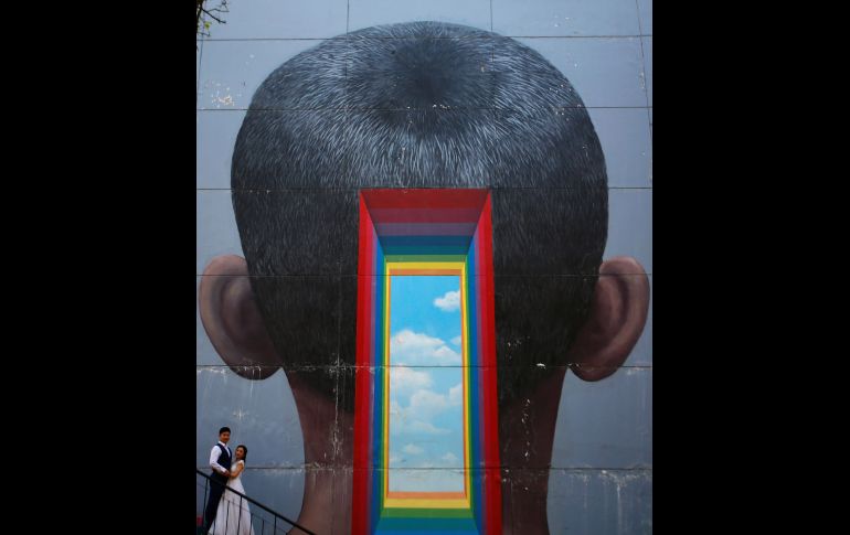 Una pareja posa para una fotografía junto a un mural en un edificio del distrito 798 de Pekín, China. EFE/ H. Hwee Young