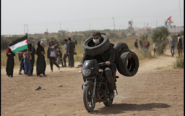 Un joven transporta varias llantas para su quema durante las protestas cerca de la frontera de Palestina con Israel, en Gaza. Por tercer viernes consecutivo, miles protestan en memoria de la Gran Marcha del Retorno junto a la frontera con Israel. EFE / M. Saber