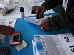 Un voluntario sella papeletas sin usar durante el conteo de votos tras el cierre de los colegios electorales. EFE/E. Biba