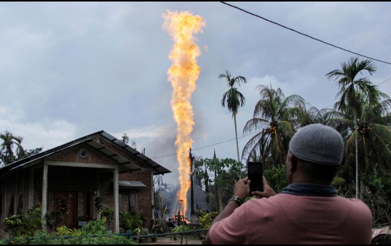 Un hombre toma fotos de un pozo petrolero en llamas en Pasir Putih, Indonesia. El pozo recién perforado de forma ilegal explotó esta mañana y provocó la muerte de al menos 15 personas. AP/Z. Maulana