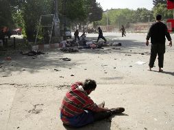 Un hombre herido permanece sentado en espera de atención médica, cerca de los cuerpos de varias víctimas de las explosiones. AP/M. Hossaini