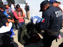 Policías estatales entregan las pertenencias de los elementos de la policía municipal a los familiares que hacen guardia afuera de la Fiscalía General del Estado. SUN