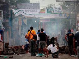 Protestantes parapetados tras una barricada en un choque con la policía. AFP/D.Ulloa
