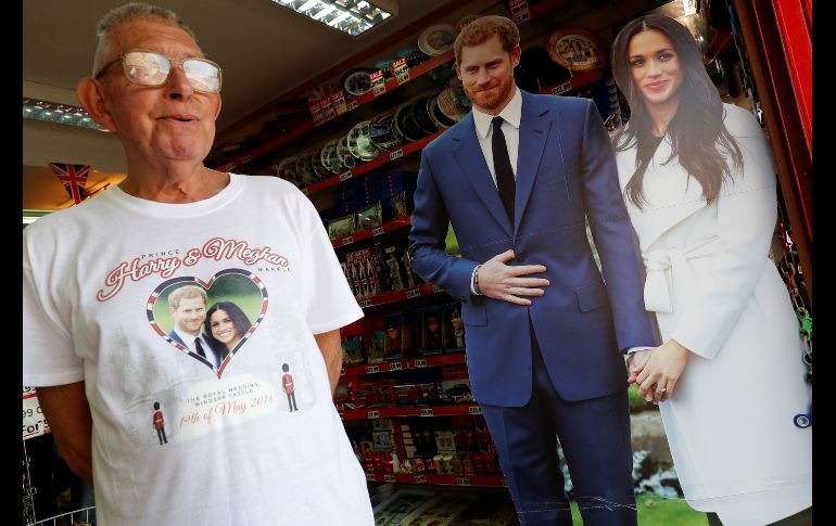 El príncipe Enrique de Inglaterra y su prometida Meghan Markle aparecen en tiendas y rincones de Windor, que albergará su boda el 19 de mayo.  Un hombre con playera alusiva al evento pasa junto a imágenes de cartón de los novios. AFP/A. Dennis
