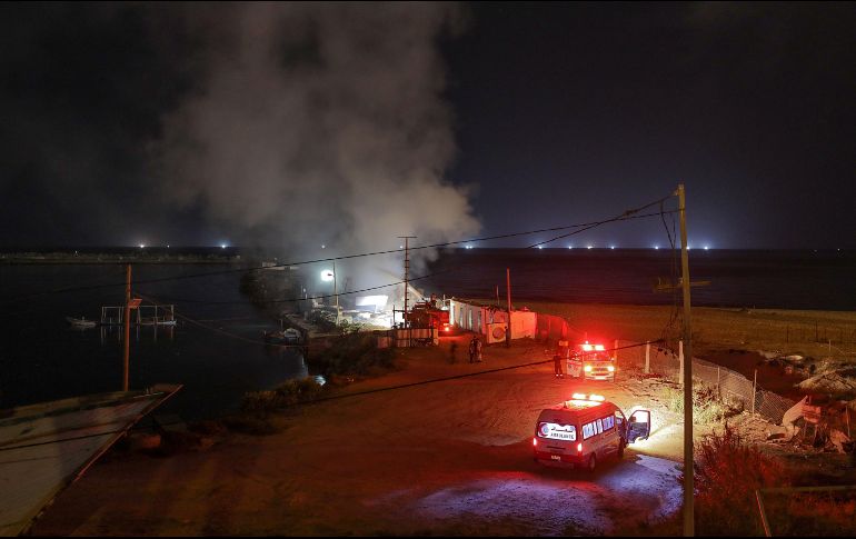 Bomberos palestinos contienen un incendio en un barco de pesca después de un supuesto ataque aéreo israelí. EFE/M. Saber