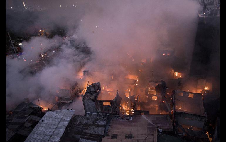 Un habitante arroja agua para combatir un incendio en un barrio de Manila, Filipinas. El fuego destruyó unas 200 casas. AFP/N. Celis