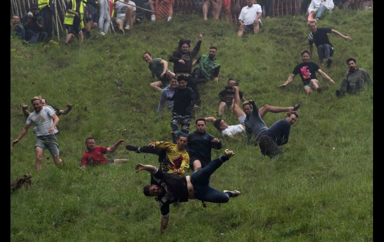Personas participan en el festival del queso rodante en Brockworth, Inglaterra. Desde la colina de Cooper se lanza un queso y los competidores corren por él cuesta abajo. AP/PA/A. Chown