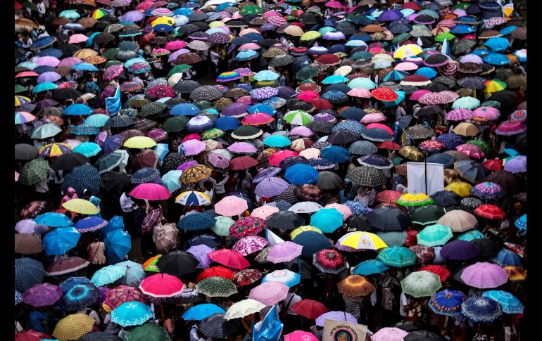 Asistentes a una marcha por la paz se cubren de la lluvia en Myitkyina, Birmania. AFP/Z. Ring Hpara