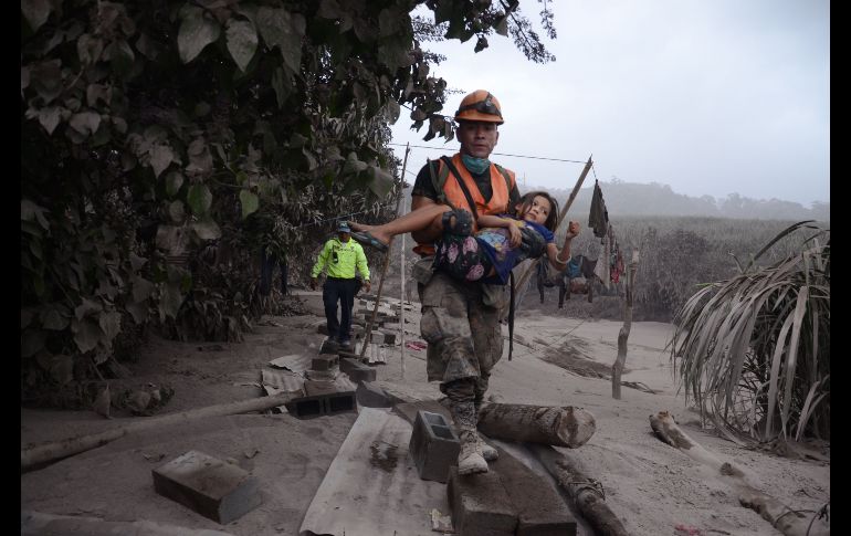 Un trabajador de los equipos de rescate de Guatemala ayuda a una niña el domingo en la población de El Rodeo.