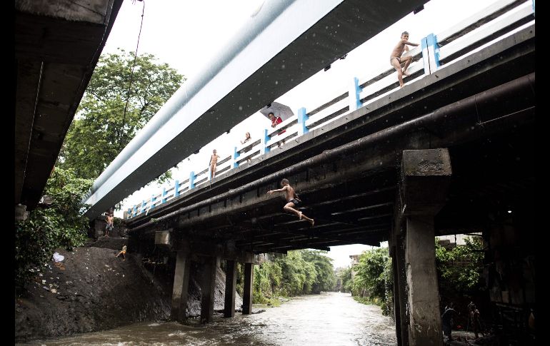 Un niño salta a un río tras fuertes lluvias en Manila, Filipinas. AFP/N. Celis