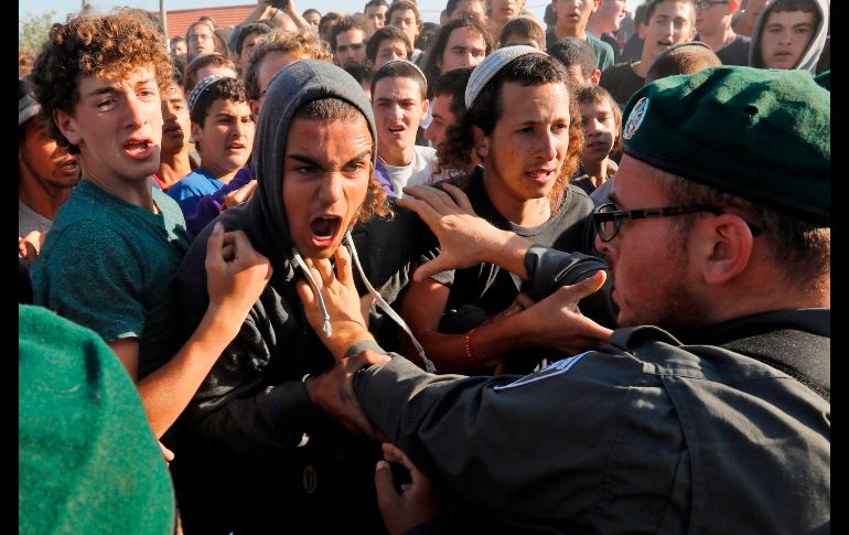 Colonos judíos discuten con policías israelíes en el asentamiento no autorizado de Netiv Haavot. Policías iniciaron el martes el desalojo de 15 viviendas construidas de forma ilegal en terrenos palestinos de propiedad privada en Cisjordania. AFP/M. Kahana