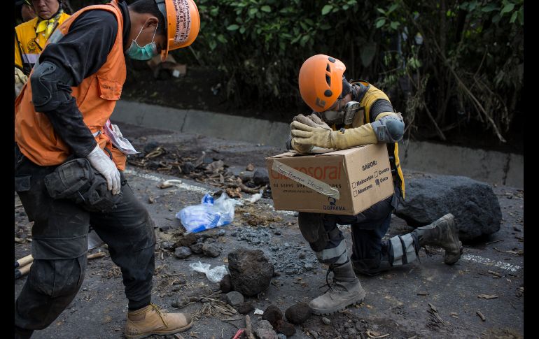Noé Cruz (d), del grupo de rescatistas mexicanos Topos Adrenalina, ora mientras sostiene restos de la familia Esqueque Iglesias, muertos a causa de la erupción del Volcán de Fuego en San Miguel Los Lotes, Guatemala. AP/R. Abd