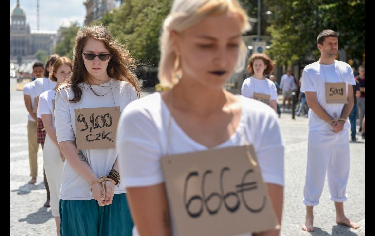 Activistas de Amnistía Internacional en Praga simulan etiquetas de precios en sus cuellos, para protestar contra la detención de refugiados en centros de Libia. AFP/M. Cizek