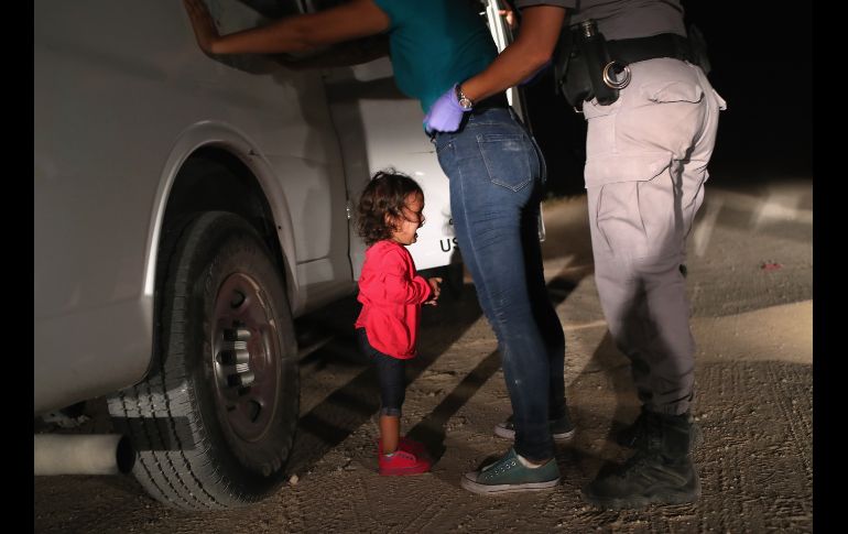 La niña comenzó a llorar cuando su madre la puso en el suelo, pues los agentes le pidieron que la soltara. AFP/J. Moore