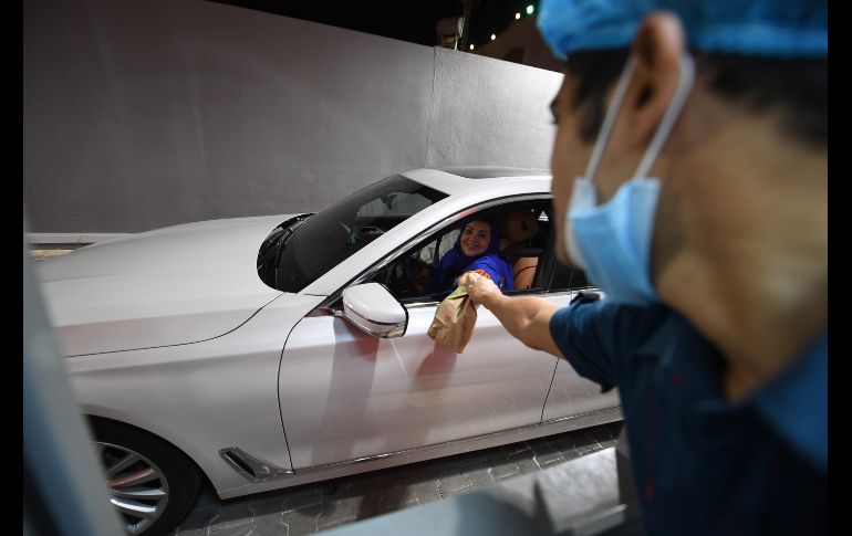 Samira Al-Ghamdi recibe comida para llevar tras hacer su pedido en auto en la ciudad de Jeddah. AFP/A. Hilabi