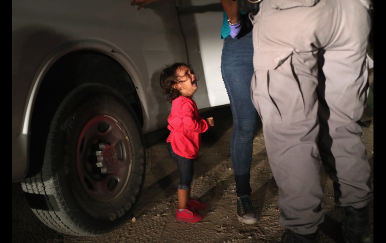 La niña comenzó a llorar cuando su madre la puso en el suelo, pues los agentes le pidieron que la soltara. AFP/J. Moore