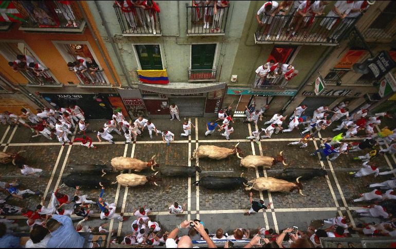 Corredores y toros a su paso por la Calle Estafeta, con toros de la ganadería de José Escolar, durante el segundo encierro de San Fermín. EFE/J.P. Urdiroz