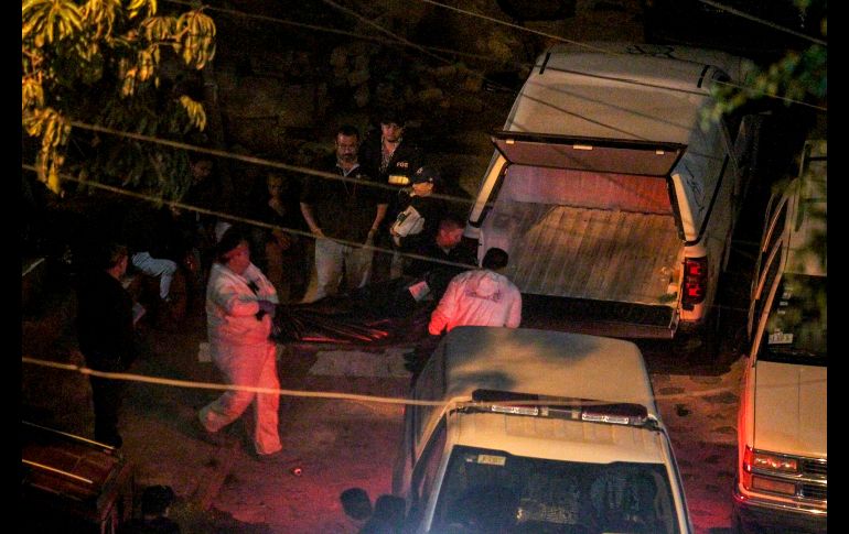 Peritos trasladan un cuerpo.