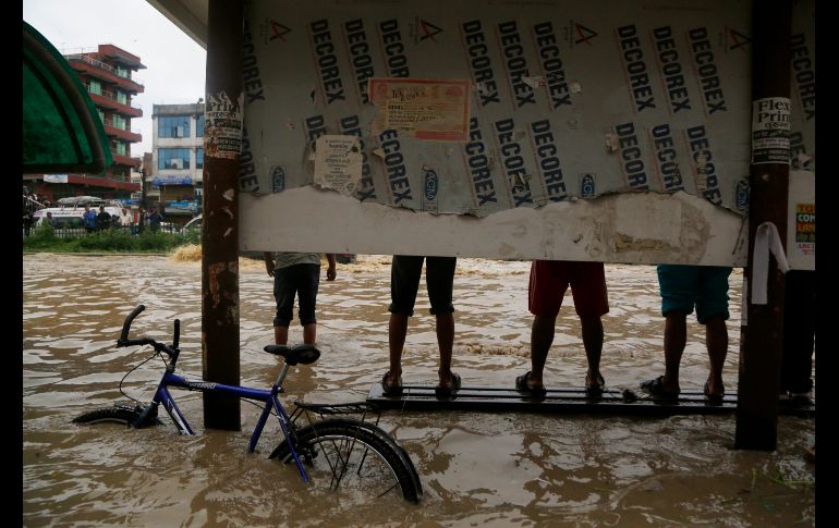 Habitantes se paran sobre una banca en una zona inundada de Bhaktapur, Nepal, luego del desbordamiento del río Hanumante por fuertes lluvias. AP/N. Shrestha
