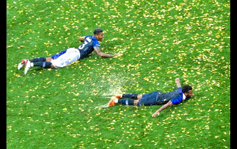 Seleccionados franceses celebran en el pasto mojado por la lluvia.