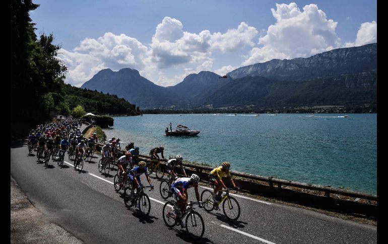 El belga Greg Van Avermaet (d), con la playera amarilla de líder, pasa con el pelotón por el lago Annecy en Le Grand Bornand, en la décima etapa del Tour de Francia. AFP/J. Pachoud