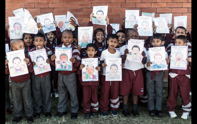Estudiantes de una primaria sostienen hojas con la imagen del fallecido líder sudafricano Nelson Mandela, durante un acto en Durban para celebrar el centenario de su nacimiento. AFP/R. Jantilal