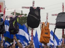 Manifestantes cargan cruces con mochilas en memoria de los estudiantes que han muerto en las protestas. EFE/J. Torres