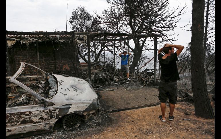 Residentes observan los destrozos registrados en una propiedad tras el paso de las llamas.