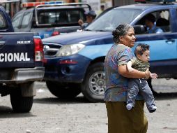Una mujer carga a un bebé mientras la policía patrulla por calles de Jinotega, Nicaragua. EFE/R. Sura