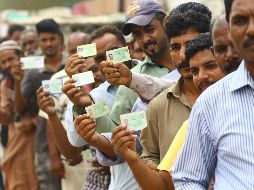 Varios votantes muestran sus documentos de identidad mientras hacen cola en un colegio electoral durante la celebración de las elecciones generales en Karachi. EFE/S. Akber