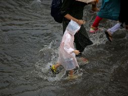 Varias personas caminan por una calle inundada en Calcuta. EFE/P. Adhikary