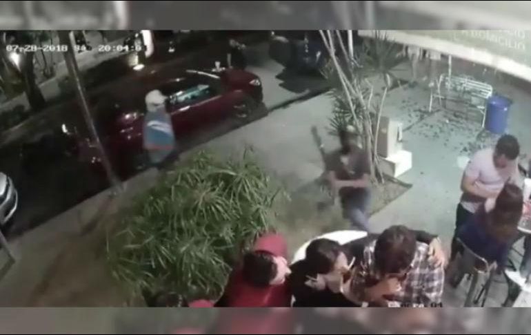 Mientras uno amaga con accionar su arma de fuego, otro comienza a golpear a un hombre con playera amarilla. TWITTER / SUN Oaxaca