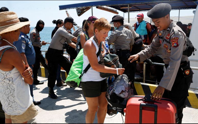 Turistas caminan con sus pertenencias tras desembarcar de un barco tras el terremoto que sacudió el norte de la isla de Lombok. EFE/A. Weda