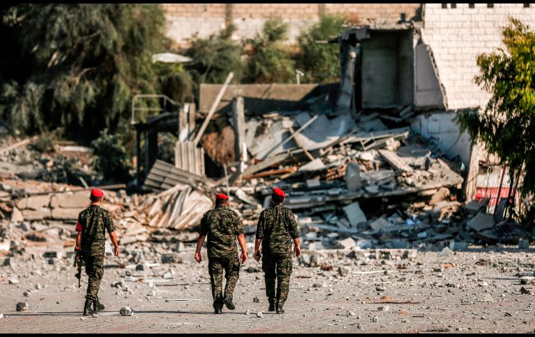 Integrantes de la policía militar de Hamas caminan por una zona dañada por bombardeos israelíes en la Ciudad de Gaza. AFP/M. Hams
