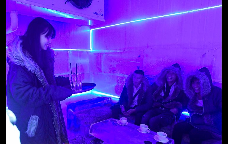 Una mesera lleva bebidas a clientes.