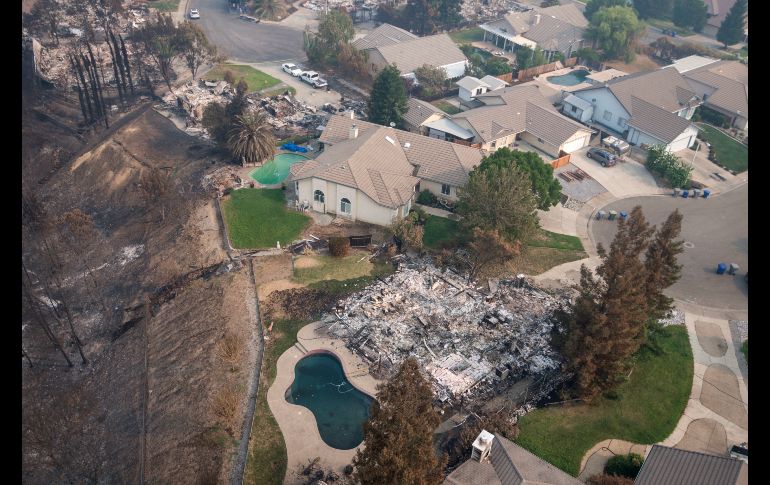 Las cenizas de una casa se ven junto a viviendas intactas por el incendio que recorrió una colonia en Redding, California. AP/M. Burke
