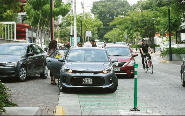 Varios automovilistas se estacionan sobre la ciclovía en López Cotilla, incluso con la tranquilidad para recoger personas, mientras un ciclista tiene que rodear su vía invadida con el riesgo que esto implica. EL INFORMADOR/F. Atilano