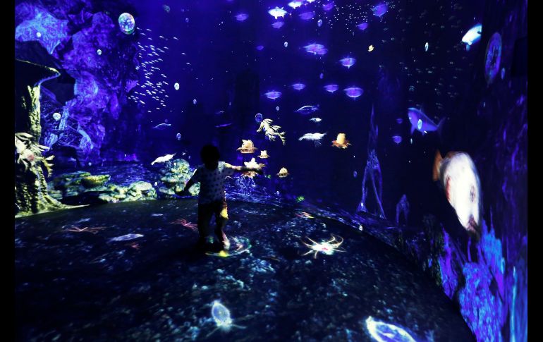 Un niño trata de parase en la instalación audiovisual 